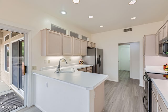 kitchen featuring sink, appliances with stainless steel finishes, light hardwood / wood-style flooring, and kitchen peninsula