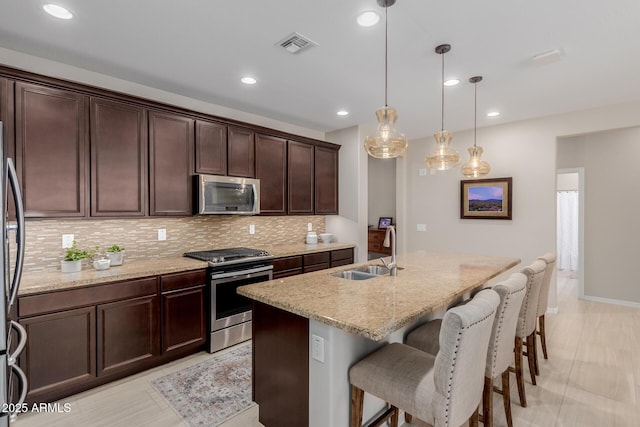 20603 W Alsap Rd, Buckeye, AZ 85396 - kitchen with appliances with stainless steel finishes, a sink, decorative backsplash, light stone countertops, and a kitchen breakfast bar