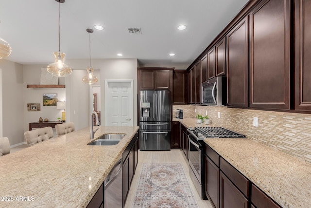 20603 W Alsap Rd, Buckeye, AZ 85396 - kitchen featuring appliances with stainless steel finishes, a sink, dark brown cabinetry, backsplash, and light stone counters