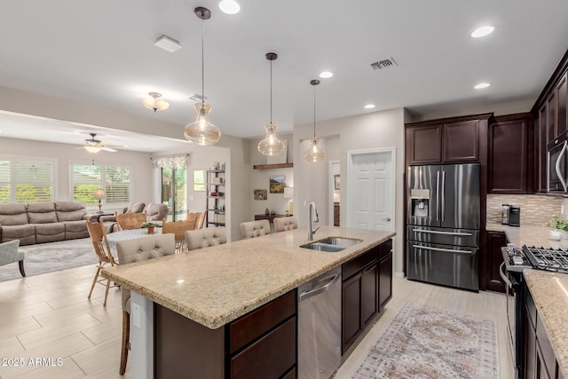 20603 W Alsap Rd, Buckeye, AZ 85396 - kitchen with appliances with stainless steel finishes, a sink, a center island with sink, backsplash, and dark brown cabinets