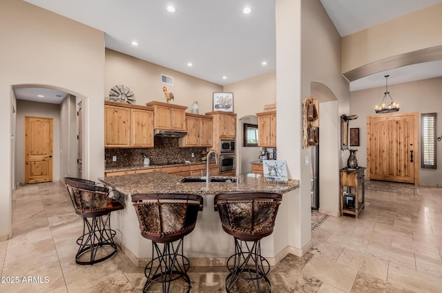 38106 N 2nd Ln, Phoenix, AZ 85086 - kitchen featuring a high ceiling, arched walkways, stainless steel appliances, under cabinet range hood, and a kitchen bar