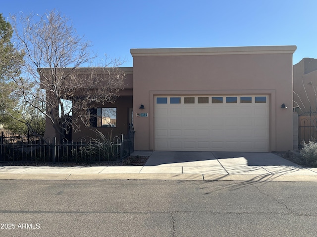 adobe home with stucco siding, concrete driveway, a garage, and fence