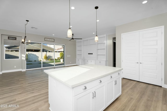 kitchen featuring visible vents, white cabinetry, light wood-style flooring, and ceiling fan with notable chandelier