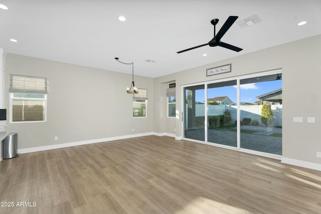 unfurnished living room featuring baseboards, visible vents, recessed lighting, ceiling fan with notable chandelier, and light wood-type flooring