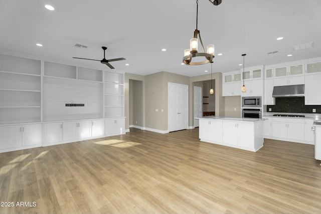 kitchen featuring visible vents, stainless steel appliances, under cabinet range hood, open floor plan, and a center island