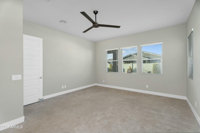 carpeted spare room featuring visible vents, baseboards, and ceiling fan