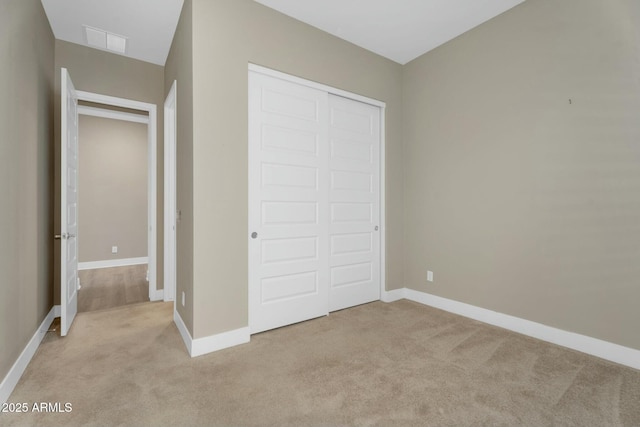 unfurnished bedroom with baseboards, visible vents, a closet, and light carpet