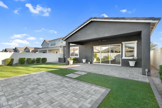 back of property featuring stucco siding, a lawn, a patio, fence, and ceiling fan