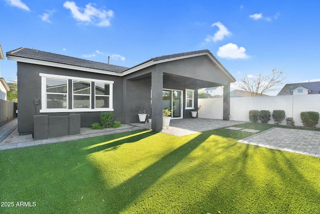 rear view of property featuring a fenced backyard, stucco siding, a yard, and a patio