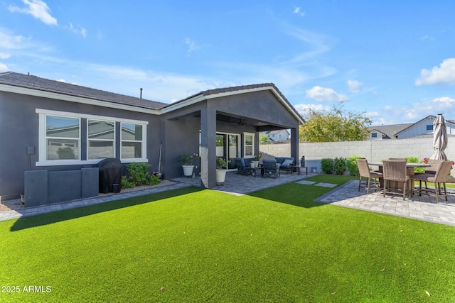 back of house with ceiling fan, fence, stucco siding, a yard, and a patio area