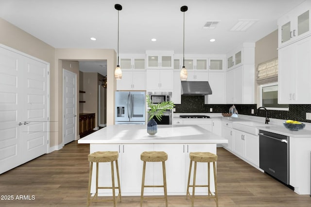 kitchen featuring visible vents, a sink, under cabinet range hood, a center island, and stainless steel appliances