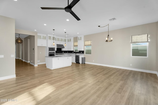 kitchen with under cabinet range hood, open floor plan, ceiling fan with notable chandelier, stainless steel appliances, and white cabinetry