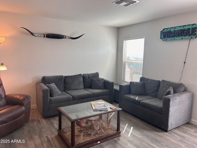 living room featuring baseboards, visible vents, and wood finished floors