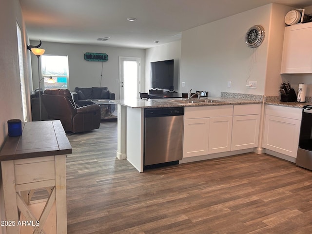 kitchen with white cabinets, open floor plan, a peninsula, stainless steel dishwasher, and a sink