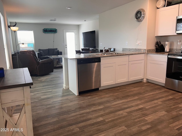 kitchen with stainless steel appliances, a peninsula, a sink, white cabinetry, and open floor plan