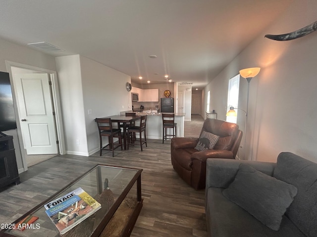 living area featuring dark wood-type flooring, recessed lighting, visible vents, and baseboards