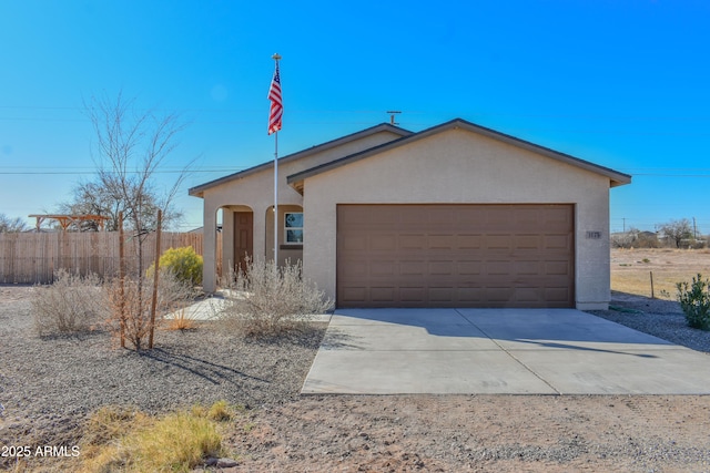 view of front of house with driveway, a garage, fence, and stucco siding