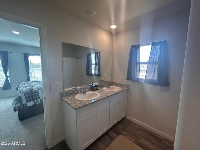 bathroom featuring double vanity, baseboards, a sink, and wood finished floors