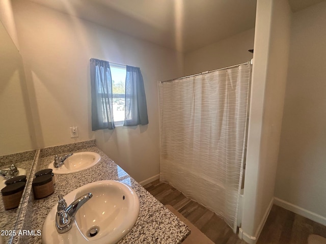 full bath with wood finished floors, a sink, shower / bath combo with shower curtain, and baseboards