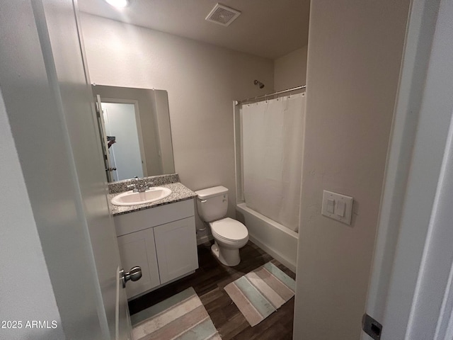 bathroom featuring visible vents, toilet, wood finished floors, shower / bath combination with curtain, and vanity