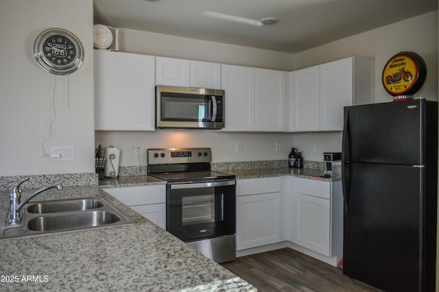 kitchen with light stone counters, dark wood-style floors, appliances with stainless steel finishes, white cabinetry, and a sink