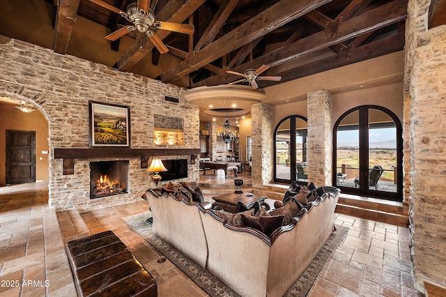 living room featuring a fireplace, beam ceiling, a towering ceiling, and ceiling fan