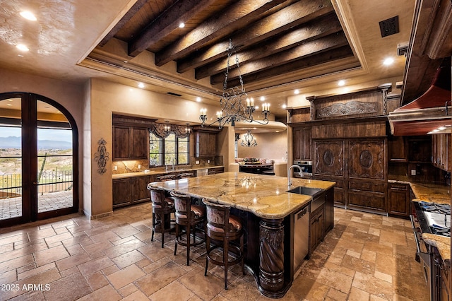 kitchen with dark brown cabinets, sink, a large island, and a healthy amount of sunlight