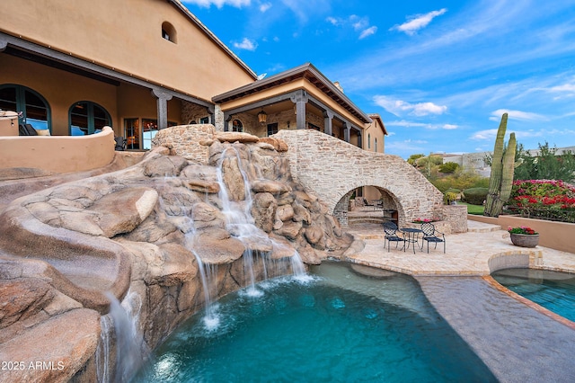 view of pool featuring pool water feature, a patio, and a jacuzzi