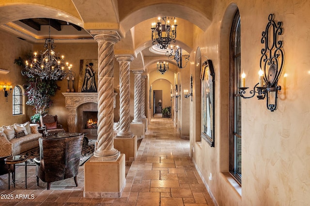 hall featuring a chandelier, a towering ceiling, and decorative columns