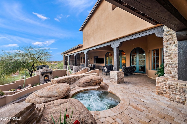 view of patio with an outdoor hot tub and an outdoor living space with a fireplace