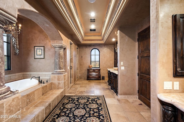 bathroom featuring a raised ceiling, a bath, decorative columns, vanity, and ornamental molding