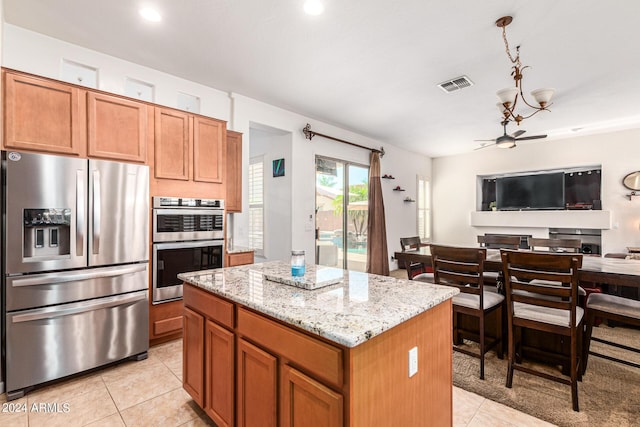 kitchen with light stone countertops, light tile patterned floors, a center island, and stainless steel appliances