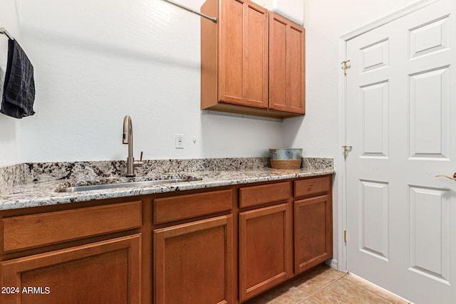 kitchen with light stone countertops, sink, and light tile patterned flooring