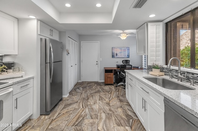 kitchen featuring white cabinetry, sink, light stone counters, and appliances with stainless steel finishes