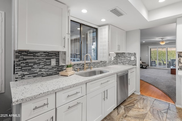 kitchen with white cabinetry, stainless steel dishwasher, sink, and light stone counters