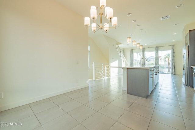 kitchen featuring an inviting chandelier, sink, hanging light fixtures, light tile patterned floors, and a center island with sink