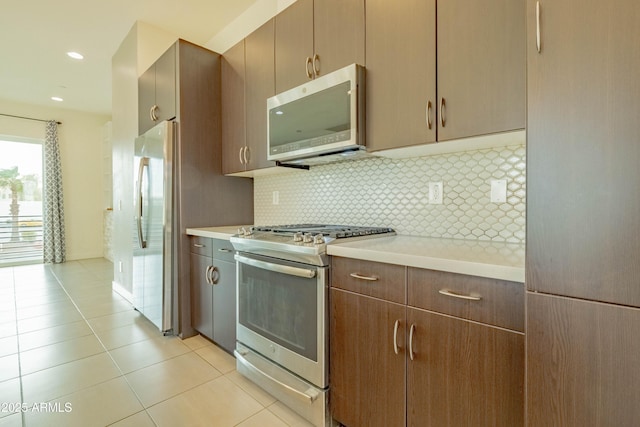 kitchen featuring backsplash, light tile patterned floors, and stainless steel appliances