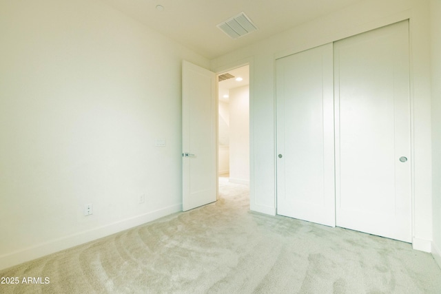 unfurnished bedroom with light colored carpet and a closet