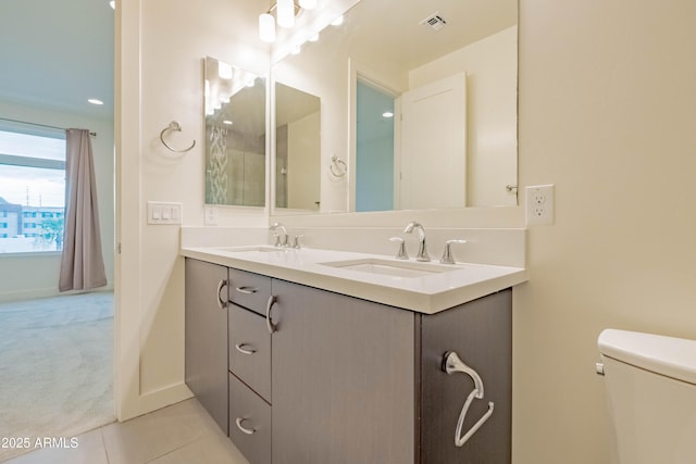 bathroom with toilet, vanity, and tile patterned flooring