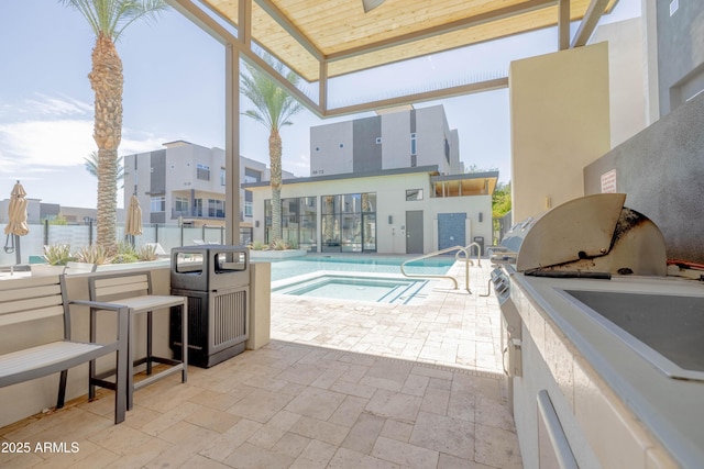 view of pool featuring grilling area, a community hot tub, a bar, exterior kitchen, and a patio