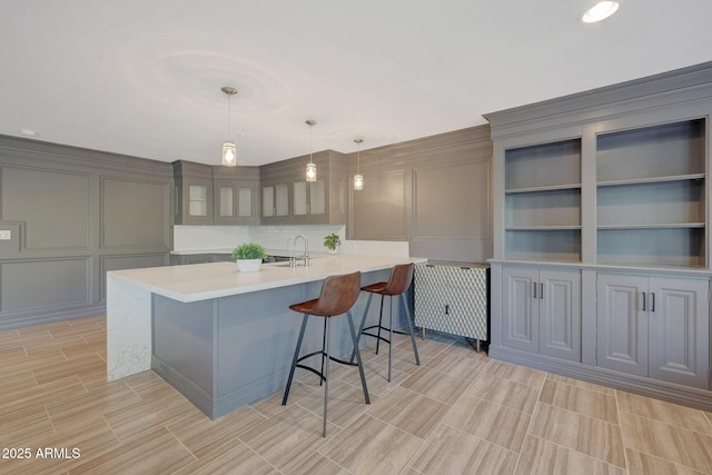 kitchen with sink, a kitchen breakfast bar, pendant lighting, gray cabinets, and built in shelves