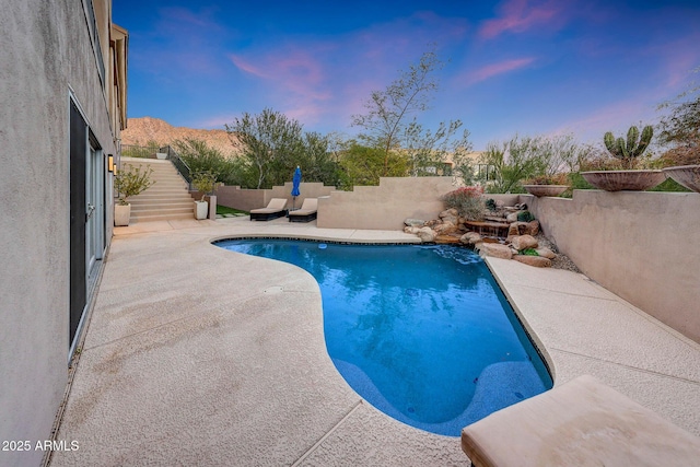 pool at dusk featuring a patio and a mountain view