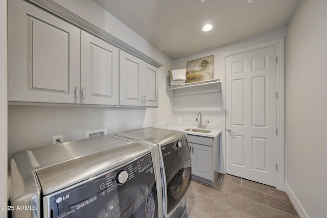 clothes washing area with cabinets, washing machine and clothes dryer, light tile patterned floors, and sink