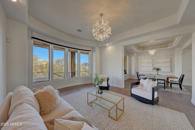 living room with hardwood / wood-style floors, an inviting chandelier, and a tray ceiling