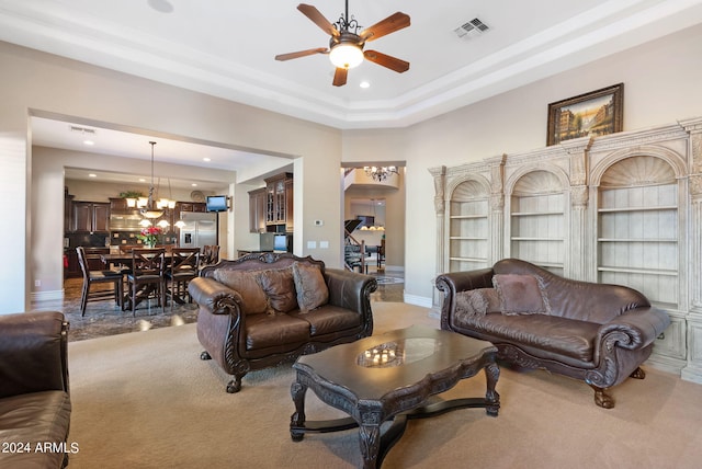 carpeted living room featuring ceiling fan with notable chandelier and a tray ceiling