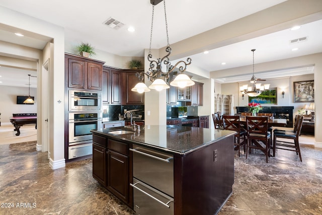 kitchen with decorative light fixtures, pool table, sink, decorative backsplash, and a center island with sink