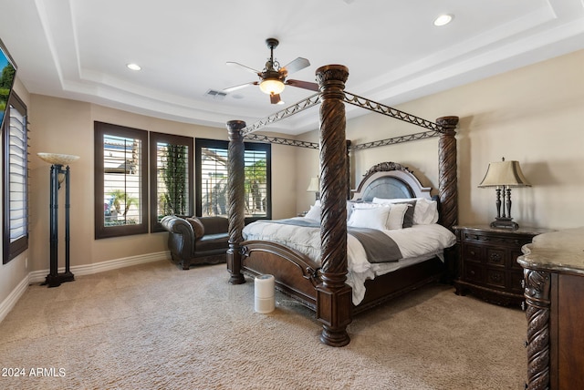 carpeted bedroom with ceiling fan and a tray ceiling