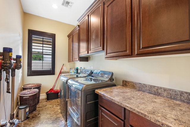 laundry area featuring dark tile patterned floors, cabinets, and washer and dryer