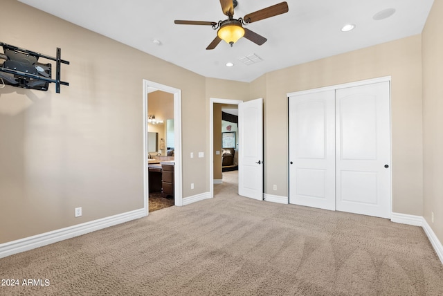 unfurnished bedroom with a closet, ceiling fan, light carpet, and ensuite bath