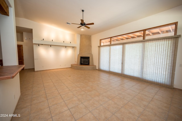 unfurnished living room featuring light tile floors, ceiling fan, a fireplace, and vaulted ceiling